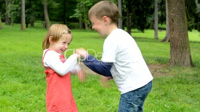 children (siblings - little boy and cute girl) playing in the park (siblings tickle)