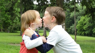 children (siblings - boy and girl) give a kiss in park