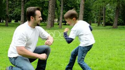 middle aged father plays with son (little boy) - park