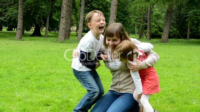 middle aged mother plays with children (boy and girl) - park