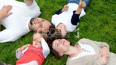 family (middle aged couple in love, boy and girl) lying in grass and talk