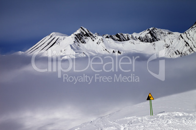 Warning sing on ski slope and mountains in fog