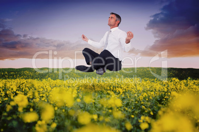 Composite image of peaceful businessman sitting in lotus pose