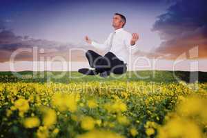Composite image of peaceful businessman sitting in lotus pose