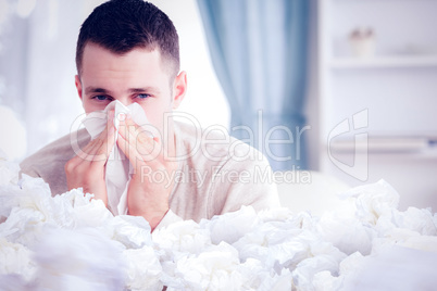 Composite image of young man blowing his nose