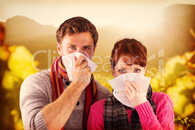 Composite image of couple blowing noses into tissues