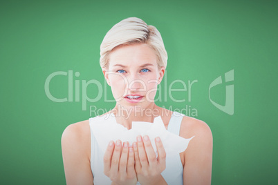 Composite image of sick woman holding tissues looking at camera