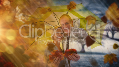 Composite image of happy mature couple showing autumn leaves und