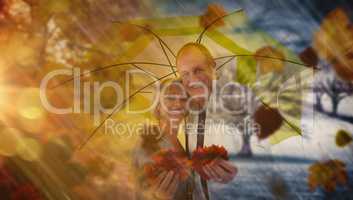 Composite image of happy mature couple showing autumn leaves und