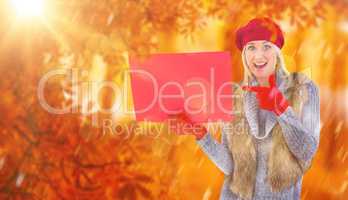Composite image of blonde in winter clothes holding red sign