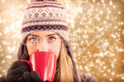 Composite image of happy blonde in winter clothes holding mug