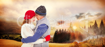 Composite image of happy couple in warm clothing hugging