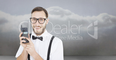 Composite image of geeky hipster holding a retro cellphone