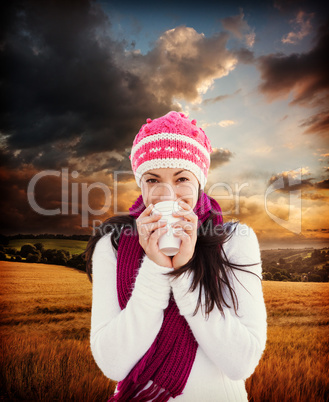 Composite image of winter brunette with coffee