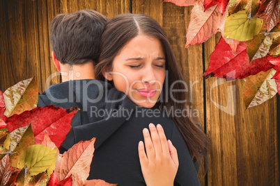 Composite image of unhappy brunette hugging her boyfriend