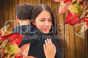Composite image of unhappy brunette hugging her boyfriend
