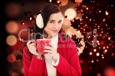 Composite image of woman in winter clothes holding a mug