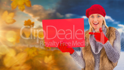 Composite image of blonde in winter clothes holding red sign