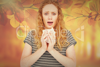 Composite image of sick woman sneezing in a tissue