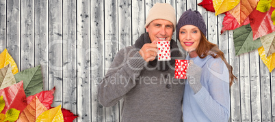 Composite image of happy couple in warm clothing holding mugs