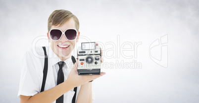 Composite image of geeky hipster holding a retro camera