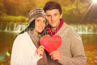 Composite image of young couple smiling holding red heart