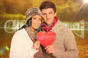 Composite image of young couple smiling holding red heart
