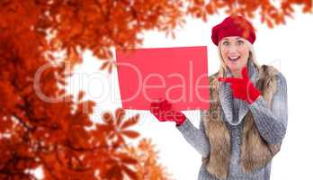 Composite image of blonde in winter clothes holding red sign