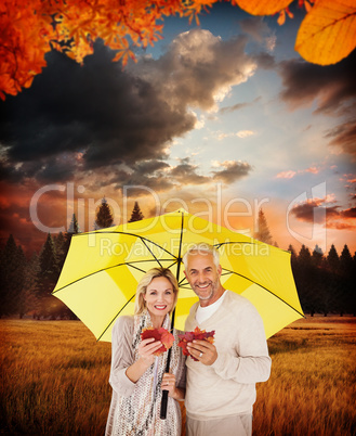 Composite image of portrait of happy couple under yellow umbrell