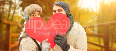 Composite image of attractive young couple in warm clothes holdi