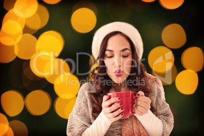 Composite image of brunette in winter clothes holding hot drink