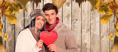 Composite image of young couple smiling holding red heart