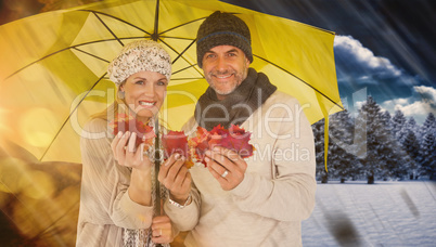 Composite image of portrait of couple holding autumn leaves whil