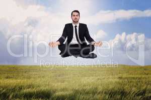 Composite image of peaceful businessman sitting in lotus pose re