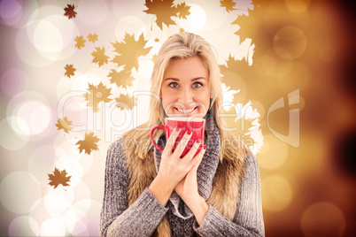 Composite image of woman in winter clothes holding a mug