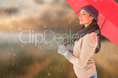 Composite image of smiling brunette holding red umbrella