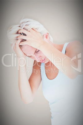 Composite image of sad blonde woman with head pain holding her h