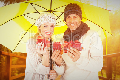 Composite image of portrait of couple holding autumn leaves whil