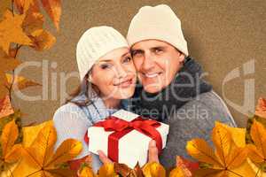 Composite image of casual couple in warm clothing holding gift