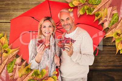 Composite image of portrait of happy couple under red umbrella