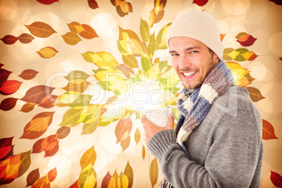 Composite image of handsome man in winter fashion holding mug