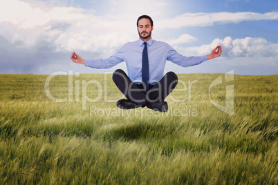 Composite image of businessman in suit sitting in lotus pose