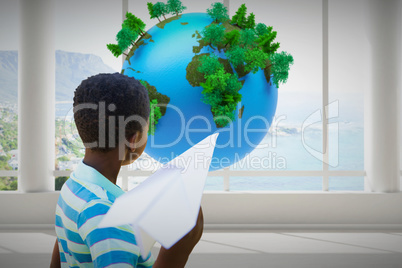 Composite image of cute little boy with paper airplane