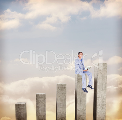 Composite image of thoughtful businessman holding book while sit