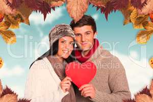 Composite image of young couple smiling holding red heart