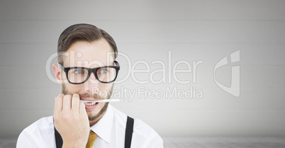 Composite image of geeky hipster biting on pencil