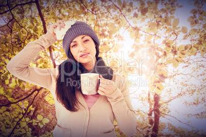 Composite image of sick brunette holding a mug and looking at th