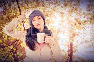 Composite image of sick brunette holding a mug and looking at th
