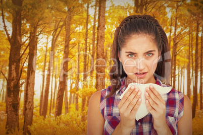 Composite image of portrait of sick woman sneezing in a tissue