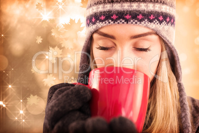 Composite image of happy blonde in winter clothes holding mug